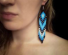 a woman wearing blue beaded earrings with black and white beads on her earring