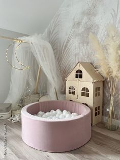 a pink bed with white rocks in it and a doll house on the floor next to it