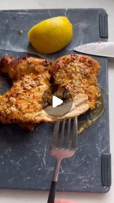 a person holding a knife and fork over a piece of meat on a plate with lemons