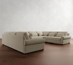 a large sectional couch sitting on top of a wooden floor next to a white wall