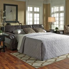 a bed sitting in the middle of a living room next to a chair and ottoman