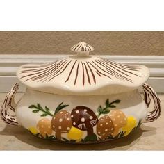 a ceramic pot with mushrooms and leaves painted on it