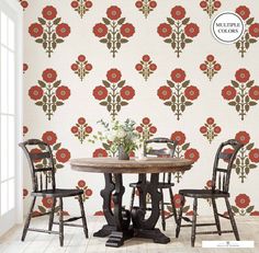 a dining room table with three chairs and a wallpaper design behind it that has red flowers