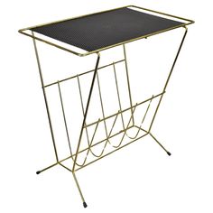 a black and gold metal table with a magazine rack on the bottom, it is isolated against a white background