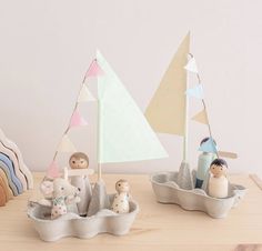 two small boats with figurines in them on a table