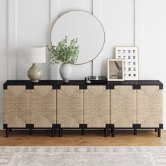 a sideboard with a mirror and vases on it next to a rug in a room