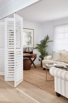 a living room with white shutters on the walls and wood flooring in it