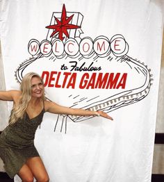 a woman posing in front of a welcome to fabulous delta gama sign with her arms outstretched