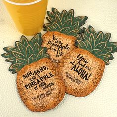 three pineapple shaped coasters next to a glass of beer on a white surface