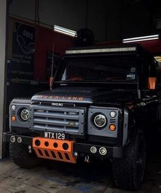 a black land rover is parked in a garage with its lights on and the front bumper light turned on