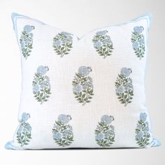 a white pillow with blue flowers and leaves on it