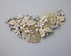 a close up of a brooch with pearls and leaves