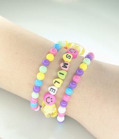 "♥ Pretty and cheery beaded bracelet set.  Pink Set ♥ Two round plastic bead bracelets in blue, pink, purple, green, yellow, and white. ♥ One pink seed beads, yellow stars, pink smiley faces, and letter beads spelling \"SMILE\" Yellow Set ♥ Two round plastic bead bracelets in blue, pink, purple, green, yellow, and white. ♥ One yellow seed beads, pink stars, yellow smiley faces, and letter beads spelling \"SMILE\" ♥ Stack the bracelets or wear them separately.    ♥ They are made out of elastic co Trendy Beaded Bracelet For Birthday, Trendy Beaded Bracelets For Birthdays, Cute Plastic Bracelets With Letter Beads, Playful Friendship Bracelets With Colorful Beads, Cute Beaded Bracelets With Letter Beads, Friendship Beaded Bracelets With Letter Beads, Trendy Colorful Beads Beaded Bracelet For Birthday, Trendy Colorful Beads Bracelet For Birthday, Trendy Colorful Beaded Bracelets For Birthday