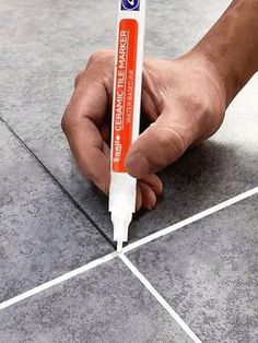 a hand holding a tube of glue on the floor