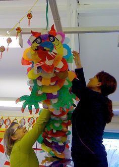 two children are trying to make a paper lion decoration hanging from the ceiling in front of them