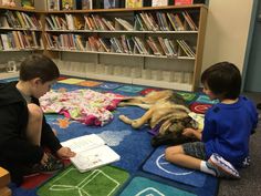 two boys and a dog are sitting on the floor in front of bookshelves