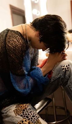 a woman sitting on top of a stool next to a man with his head down