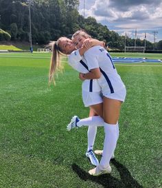 two female soccer players hugging each other on the field