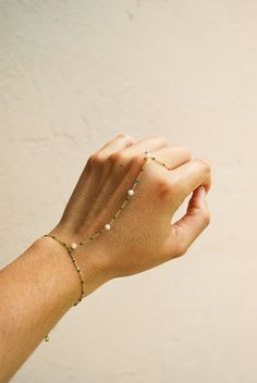 ☞ Features  ✤ Minimalist gold beaded hand chain bracelet with freshwater pearl accents and green enameled beads. ✤ All parts of the necklaces are made of a thick and sturdy 18k gold plated material along with freshwater pearls and green enamel beads. ☞ Measurements:  ✤ Bracelet Length: 6 in - Extender: 1 in - Wrist to finger length: 3.5 in  ✤ Ring sized to fit fingers US 3 - 9 in inches. ✤ Freshwater Pearls : 4 mm  ✤ Model wears bracelet at 6 inches  ✤ Gently Handmade and Polished  ☞ Shipping ✤ Dainty Adjustable Beaded Bracelets With Pearl Chain, Delicate Beaded Chain Bracelet As Gift, Delicate Beaded Bracelets With Adjustable Chain, Dainty Beaded Chain Bracelet For Gift, Adjustable Bohemian Bracelet With Delicate Chain, Dainty Beaded Bracelet For Gifting, Dainty Beaded Chain Bracelet As Gift, Dainty Gold-plated Jewelry With Tiny Beads, Dainty Beaded Jewelry With May Birthstone