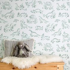 a stuffed animal sitting on top of a wooden bench in front of a wallpaper