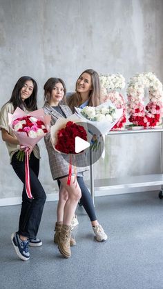 three girls are holding flowers in front of a table with red and white bouquets