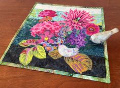 a wooden table topped with a quilted place mat and a bird on top of it