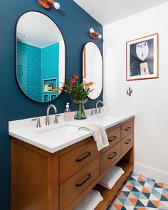 a bathroom with two sinks and mirrors on the wall next to a blue tiled floor