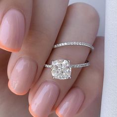 a woman's hand with a ring and a diamond on her left hand, holding a white manicure