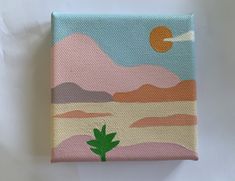 a painting on canvas with mountains in the background and a green plant growing out of it