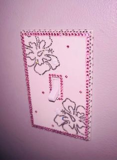 a pink light switch cover with beads and flowers on it in a girls'room