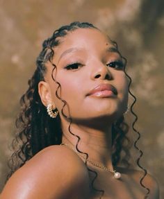 a close up of a woman with long hair and earrings on her head, looking off to the side