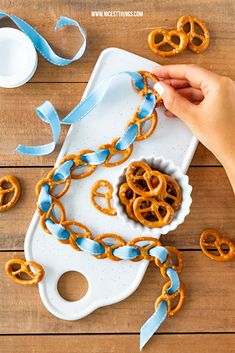 the pretzels are being cut into small pieces and placed on a tray with blue ribbon