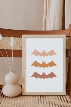 three bat silhouettes are displayed in front of a white vase on a wicker table