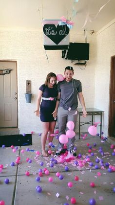 a man and woman standing next to each other in front of pink and purple balloons