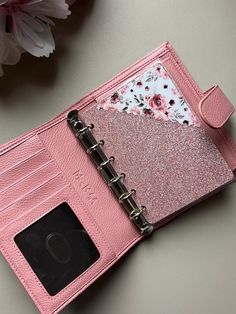 an open pink planner book sitting on top of a table next to a flower bouquet