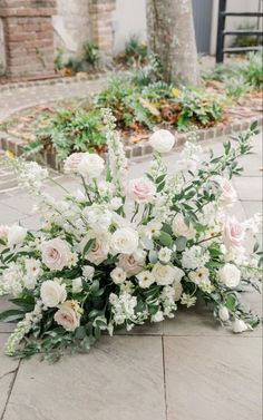 a bunch of white flowers sitting on top of a stone floor in front of a building