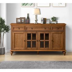 a wooden sideboard sitting on top of a hard wood floor next to a plant