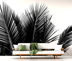 a couch sitting in front of a palm tree wall mural