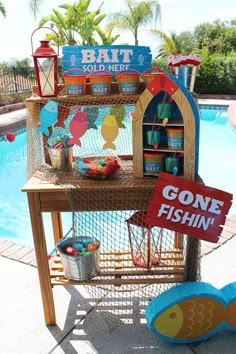 a table with a sign that says gone fishin'on it next to a swimming pool