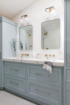 a bathroom with two sinks, mirrors and blue cabinetry in the middle of it