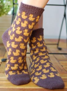 a woman's legs wearing socks with yellow and brown designs on them, sitting on a wooden floor