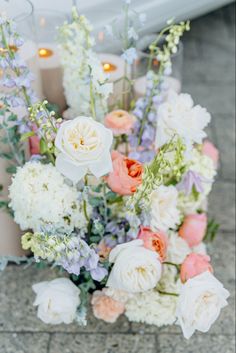 an arrangement of flowers and candles on the ground