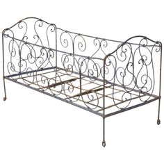 a metal bed frame with wheels on the bottom and sides, in an ornate pattern