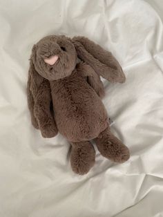 a brown stuffed animal sitting on top of a white sheet