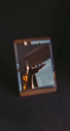 the reflection of a hand reaching out from behind a mirror