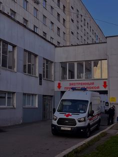 an ambulance parked in front of a building with two men standing next to the van