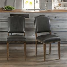 two black leather chairs sitting in front of a kitchen counter