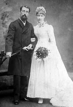 an old black and white photo of a man and woman dressed in formal attire, holding a cane