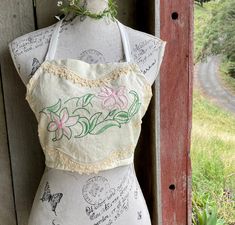 a mannequin is adorned with flowers and writing on it's back, in front of a wooden fence