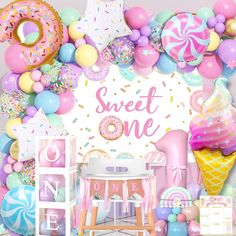 a birthday party with balloons, confetti and donuts on the wall in front of it